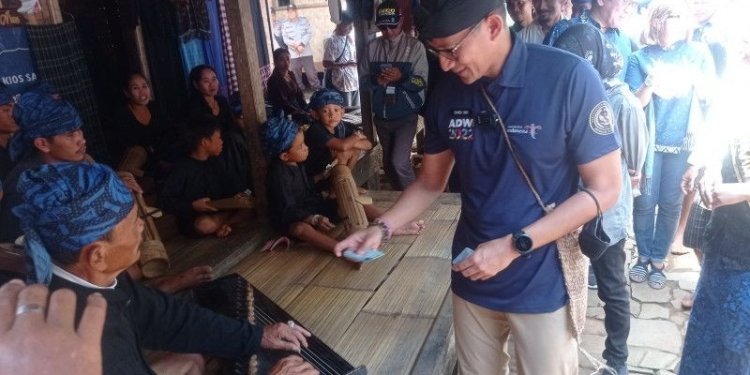 Sandiaga Uno memberikan uang Rp ribu kepada pemain pemusik tradisional masyarakat Badui di pedalaman Kabupaten Lebak, Sabtu (15/10). ANTARA/Mansur