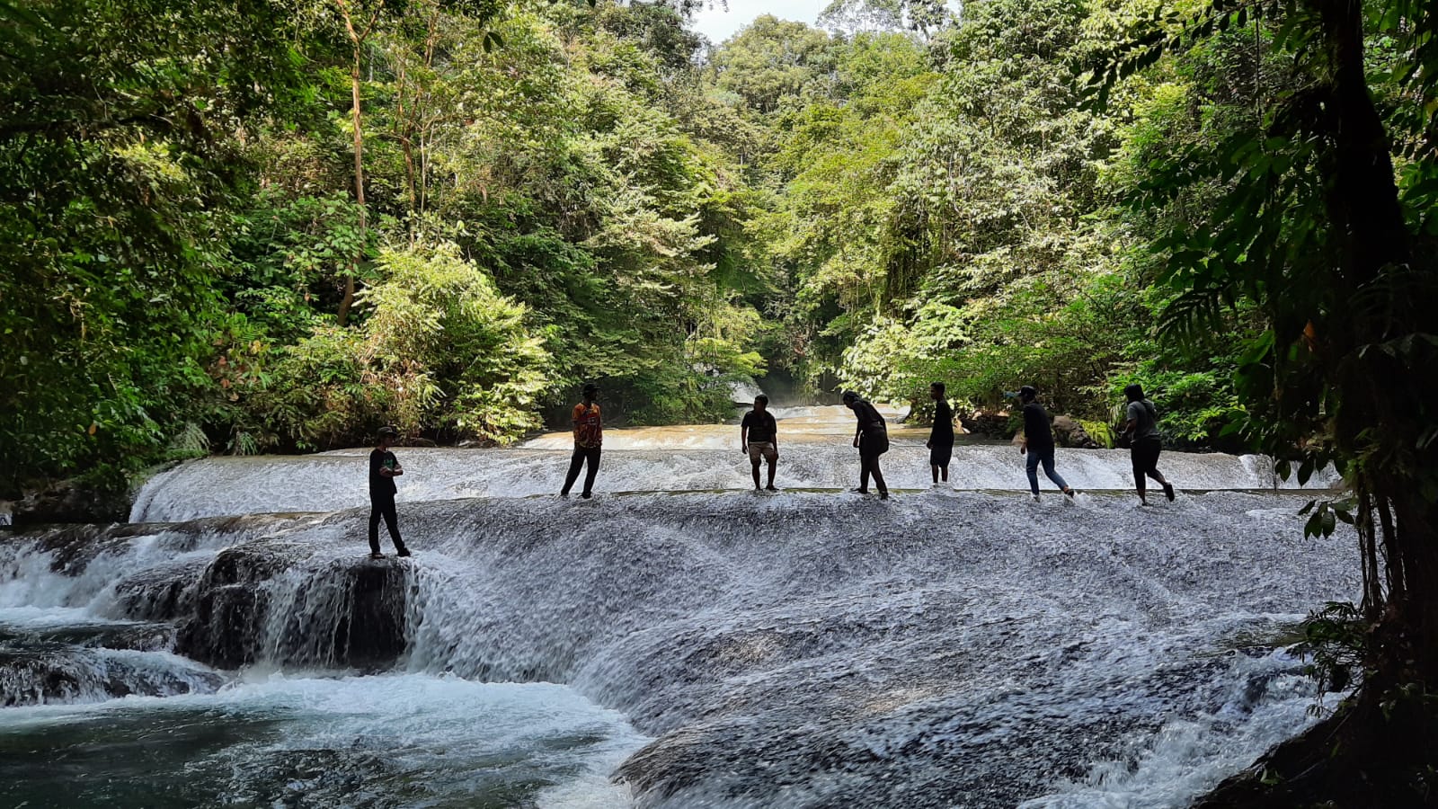 Para wisatawan berswafoto di aliran Air Terjun Tujuh Bidadari. (Doc. ALIBI.id).