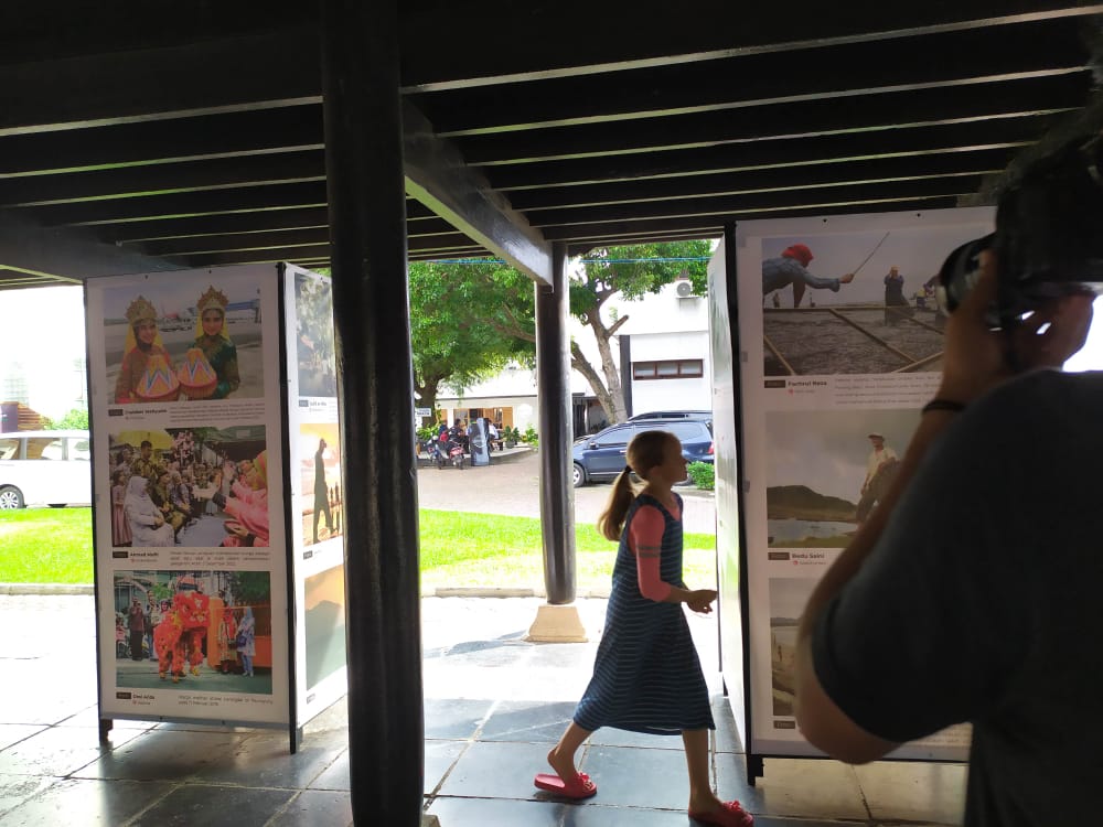 Seorang anak wisatawan asing berjalan di antara foto yang dipamerkan PFI Aceh. (Dok. Fahzi Aldevan)