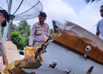 Tampak anggota kepolisian memeriksa sebuah puing mirip badan pesawat yang ditemukan warga pesisir Pantantai Air Danau, Sejuba, Desa Sepempang, Natuna, Kepri, Sabtu (24/12). (ANTARA/Cherman)