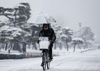 Arsip - Seorang pria mengendarai sepeda di tengah hujan salju saat pandemi COVID-19, di Tokyo, Jepang (6/1/2022). ANTARA FOTO/REUTERS/Issei Kato/aww.