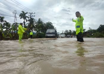 Personel Satlantas Polres Pidie bantu pengendara lewati banjir, Sabtu (21/1/2023). (Dok. Polisi)