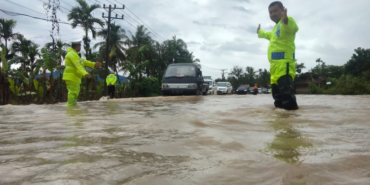 Personel Satlantas Polres Pidie bantu pengendara lewati banjir, Sabtu (21/1/2023). (Dok. Polisi)