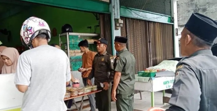 Petugas Wilayatul Hisbah (WH) menegur pedagang yang menjual makanan di siang hari saat bulan suci Ramadhan 1444 Hijriyah, di ruas Jalan Merdeka, Meulaboh, karena melanggar ketentuan syariat Islam dan meminta toko tersebut ditutup, Sabtu (25/3/2023). (Foto: Antara/Ho-Dok Satpol PP WH Aceh Barat)