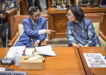 Menkopolhukam sekaligus Ketua Komite TPPU Mahfud MD (kiri) berbincang dengan Menkeu Sri Mulyani saat mengikuti rapat dengar pendapat bersama Komisi III DPR di Kompleks Parlemen, Senayan, Jakarta, Selasa (11/4/2023). (Foto: Antara/Galih Pradipta/hp)