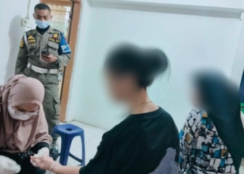 Petugas melakukan tes darah terhadap wanita yang terjaring razia asusila di Padang. (Foto: Antara/HO Satpol PP Padang)