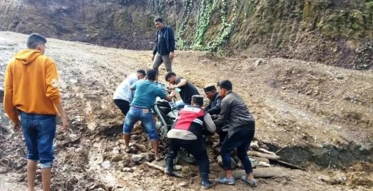 Warga bersama petugas kepolisian membantu mengevakuasi pengendara sepeda motor yang terjebak tanah longsor di badan jalan provinsi di kawasan Simpang Baibon, Kecamatan Sungai Mas, Kabupaten Aceh Barat, Senin (8/5/2023). (Foto: Antara/HO)