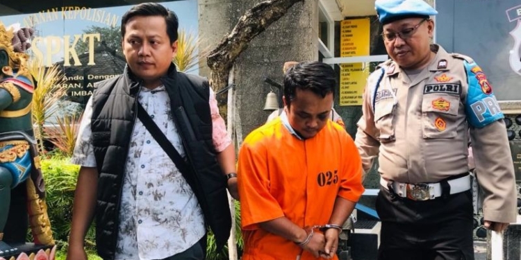 Personel Kepolisian Sektor Kuta menggiring tersangka Agus Budianto yang terlibat kasus penganiayaan terhadap seorang sopir bus di Polsek Kuta, Badung, Bali, Rabu (31/5/2023). (Foto: Antara/Rolandus Nampu)