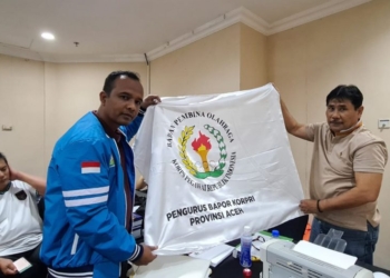 Wakil Ketua Kontingen Korpri Aceh, Firdausi, menyerahkan bendera kontingen kepada pihak panitia Pornas Korpri XVI, di Semarang, Rabu (12/7/2023). (Foto: Alibi/Dok. Humas Pemerintah Aceh)