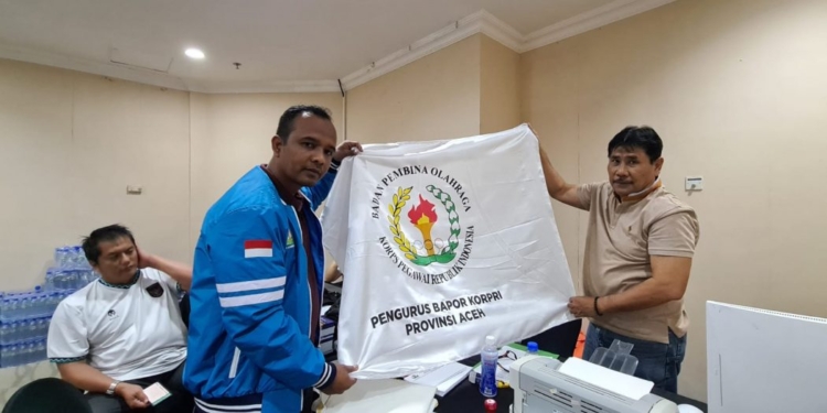 Wakil Ketua Kontingen Korpri Aceh, Firdausi, menyerahkan bendera kontingen kepada pihak panitia Pornas Korpri XVI, di Semarang, Rabu (12/7/2023). (Foto: Alibi/Dok. Humas Pemerintah Aceh)