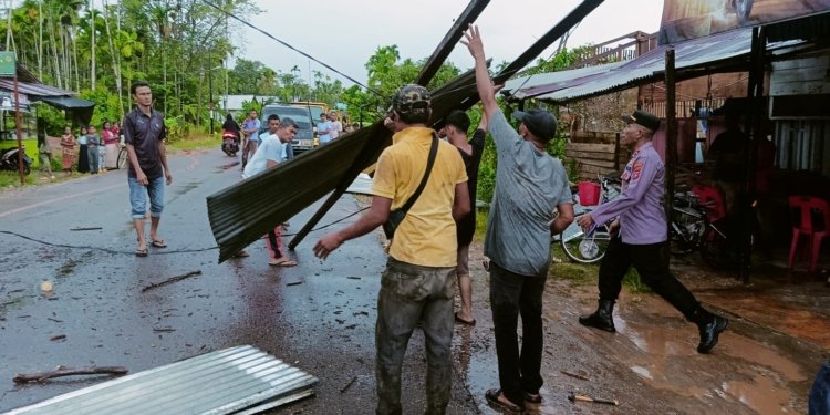 Warga dan petugas kepolisian membersihkan material bangunan yang rusak akibat angin kencang di Aceh Utara. (Foto: Alibi/Dok. Polres Aceh Utara)