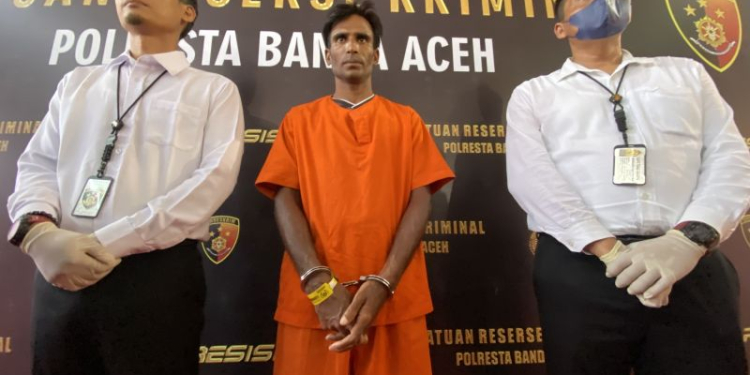 Satreskrim Polresta Banda Aceh mengawal seorang warga etnis Rohingya Muhammed Amin (tengah) yang ditetapkan sebagai tersangka dalam kasus dugaan tindak pidana penyeludupan manusia ke Indonesia di Mapolresta Banda Aceh, Aceh, Senin (18/12/2023). (Foto: Antara/Khalis)