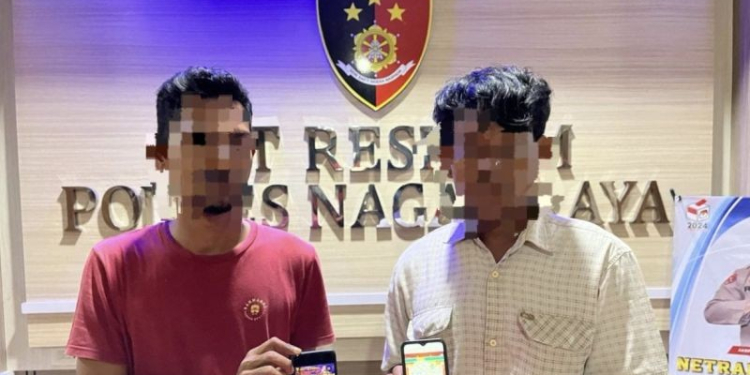 Kepolisian memperlihatkan dua pelaku judi slot daring saat diamankan di Mapolres Nagan Raya, Aceh, Rabu (1/5/2024). (Foto: Alibi/HO-Polres Nagan Raya)