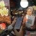 Pedagang melayani konsumen yang memindai kode sistem pembayaran Quick Response Code Indonesian Standard (QRIS) saat berbelanja di gerai kuliner Pesta Rakyat, Banda Aceh, Aceh, Jumat (26/7/2024). (ANTARA FOTO/Khalis Surry)